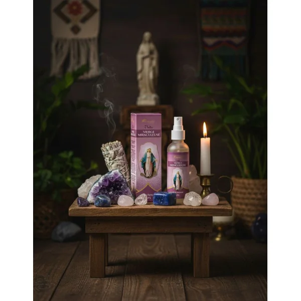 Flacon et boîte du spray parfumé Vierge Miraculeuse disposés sur une petite table style autel avec cristaux