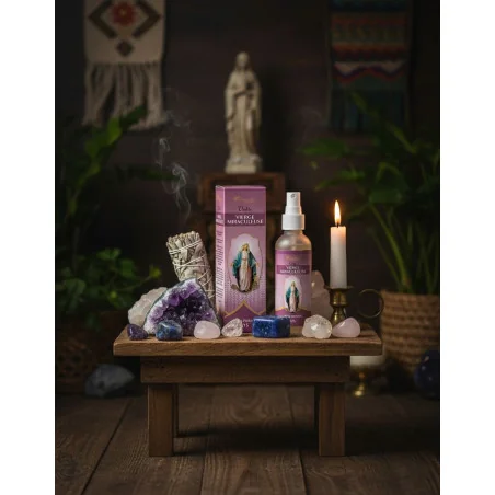 Flacon et boîte du spray parfumé Vierge Miraculeuse disposés sur une petite table style autel avec cristaux