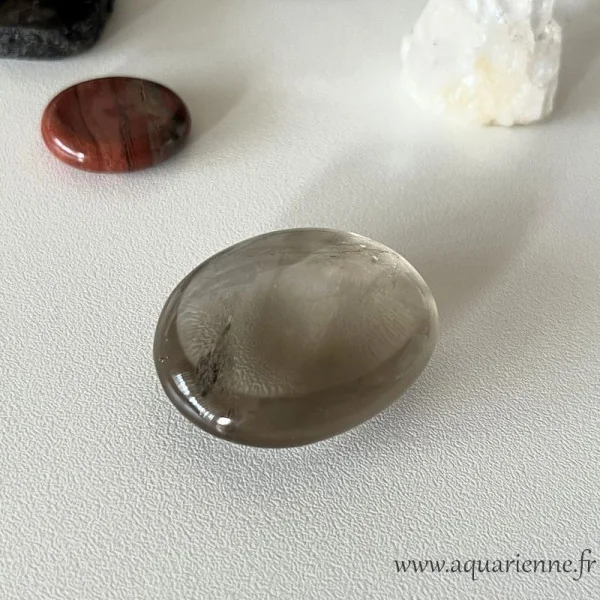Photo de ce galet poli de quartz fumé prise en intérieur à la lumière du jour. Protection et ancrage avec le quartz fumé.