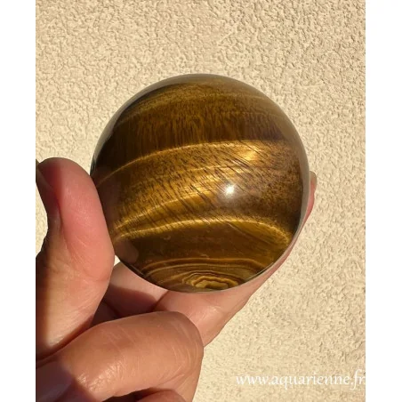 Reflets brun doré chatoyants pour cette sphère en Œil de Tigre, pierre de protection, de courage et de volonté.